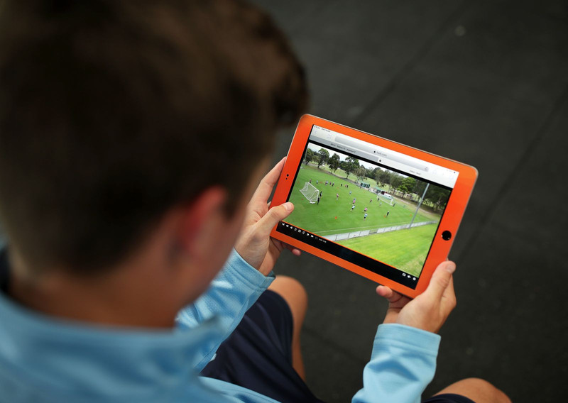 Homem assistindo a um vídeo de uma partida de futebol em um tablet